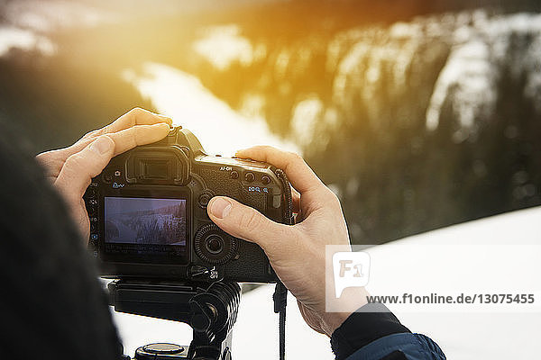 Ausschnitt eines Mannes  der mit einer Digitalkamera auf einem schneebedeckten Berg fotografiert