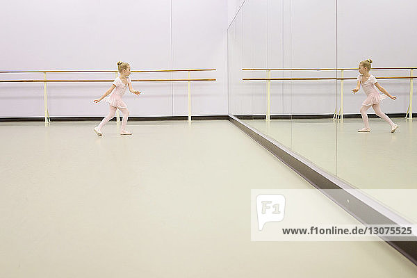 Girl practicing ballet in front of mirror at ballet studio
