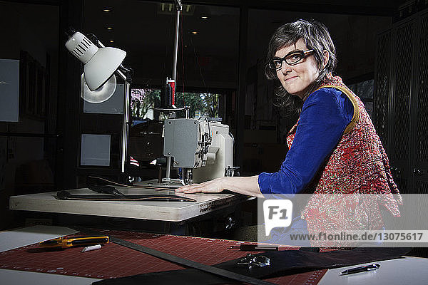 Porträt einer Frau mit Nähmaschine in der Werkstatt
