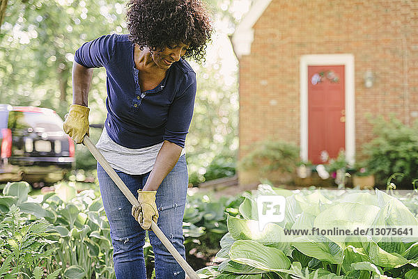 Mature woman using gardening fork while working in yard