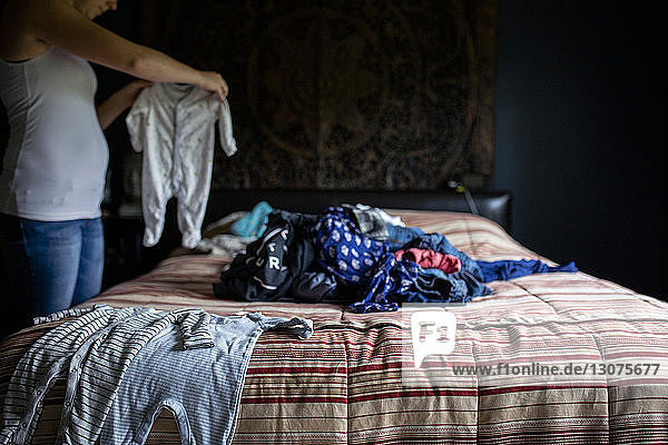 Mitschnitt einer Frau  die im Schlafzimmer stehend Wäsche hält