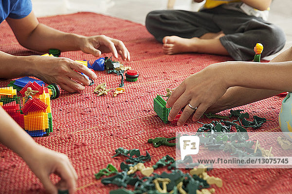 Ausgeschnittenes Bild einer Familie  die zu Hause mit Spielzeug auf dem Boden spielt