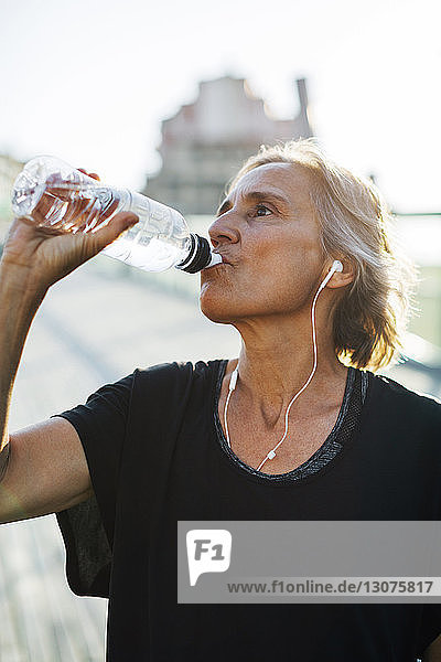 Frau trinkt Wasser beim Musikhören