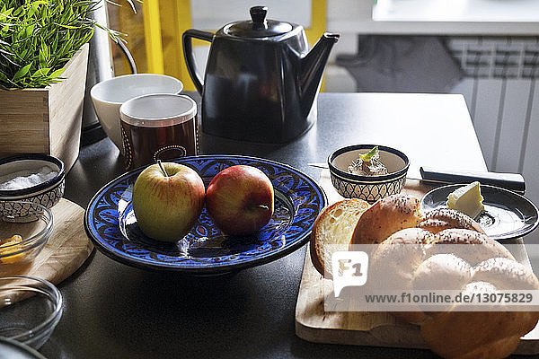 Nahaufnahme eines Brotlaibs mit Äpfeln und Tee auf dem Tisch