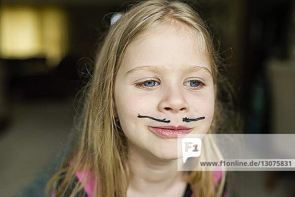 Mädchen mit Schnurrbart-Gesichtsbemalung zu Hause