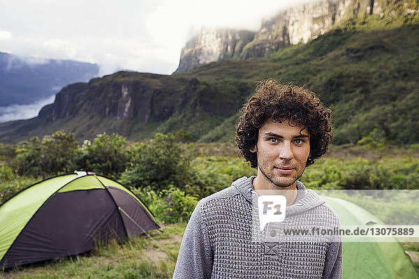 Portrait of confident man standing at campsite on mountain