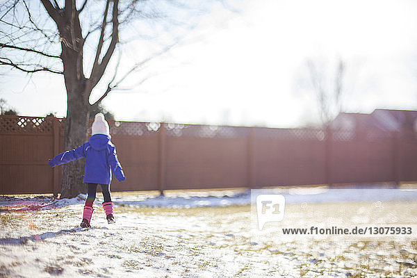 Rückansicht eines Mädchens  das auf einem schneebedeckten Feld im Hof läuft