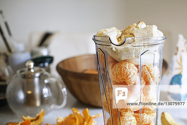 Clementinen und Bananen im Mixer mit Schalen auf dem heimischen Tisch