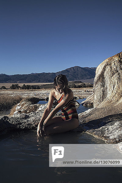 Woman sitting on rock and relaxing at Bridgeport Hot Springs