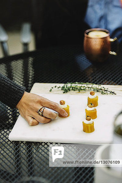 Cropped image of woman table appetizer served on white board in backyard