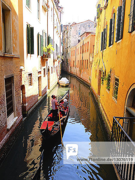 Man rowing gondola on Grand Canal amidst buildings