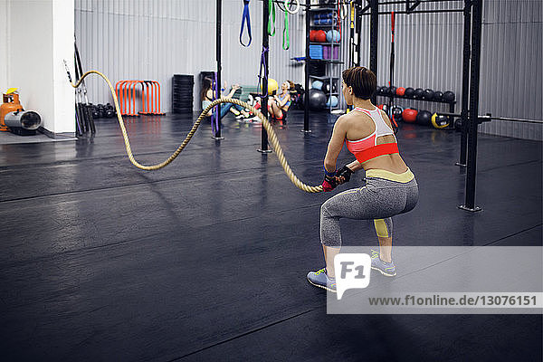 Rückansicht einer entschlossenen Sportlerin  die mit Seil in der Turnhalle trainiert