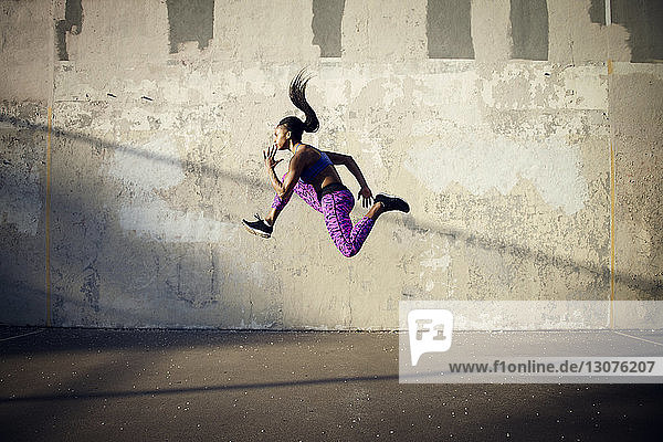 Seitenansicht einer Frau  die in der Luft gegen eine Wand springt