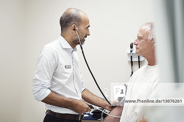 Seitenansicht des Arztes  der den Blutdruck des Patienten im Krankenhaus überprüft