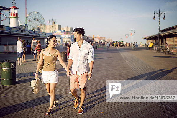 Paar hält sich beim Gehen am Pier an den Händen