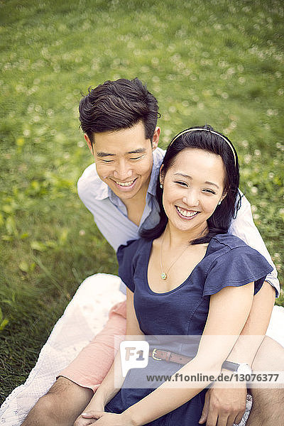 Hochwinkelansicht eines lächelnden Paares  das sich auf dem Feld entspannt