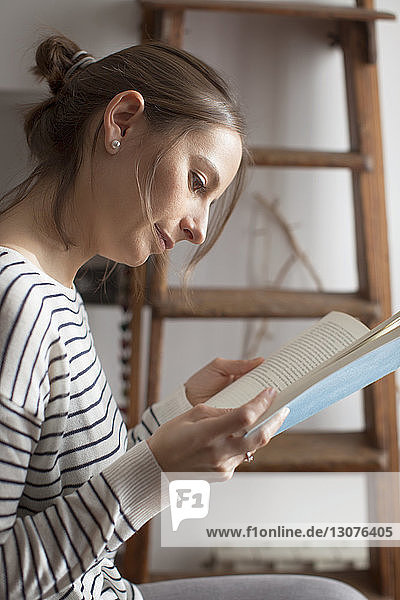 Close-up of woman reading book while sitting at home