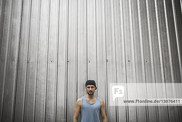 Serious man standing against metallic wall