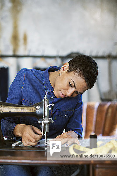 Junge Modedesignerin arbeitet in einem Workshop an einer Nähmaschine