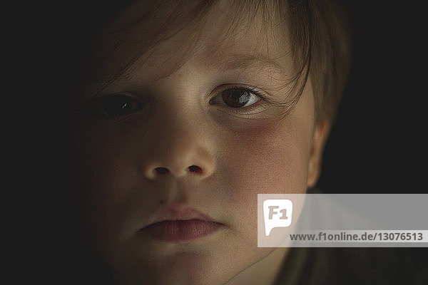 Nahaufnahme-Porträt eines süßen Jungen in einem dunklen Raum