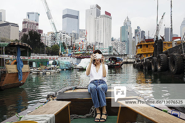 Frau fotografiert  während sie in der Stadt auf einem Boot sitzt
