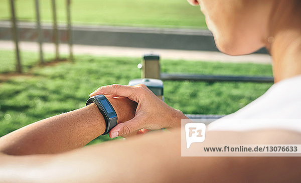 Ausgeschnittenes Bild einer Frau  die beim Sport im Park auf eine intelligente Uhr schaut