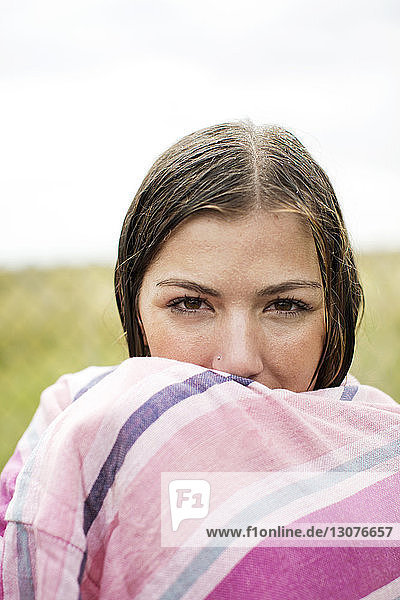 Porträt einer nassen  in ein Handtuch gewickelten Frau auf dem Hof