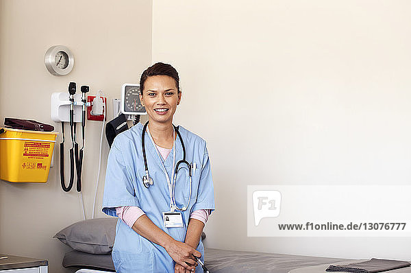 Portrait of female doctor standing in medical examination room