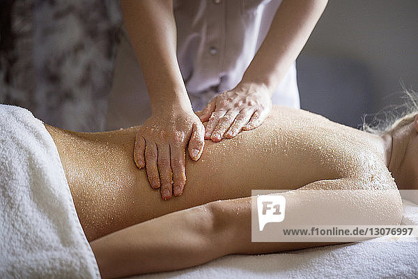 Midsection of female therapist massaging woman's back in spa