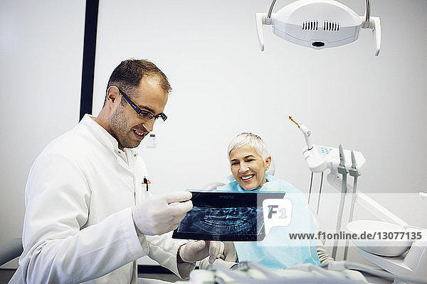 Dentist explaining x-ray to smiling patient at clinic