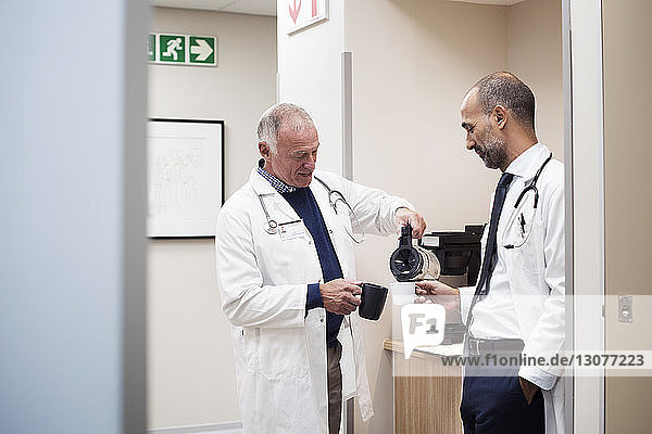 Doctors having coffee while standing in hospital seen through door