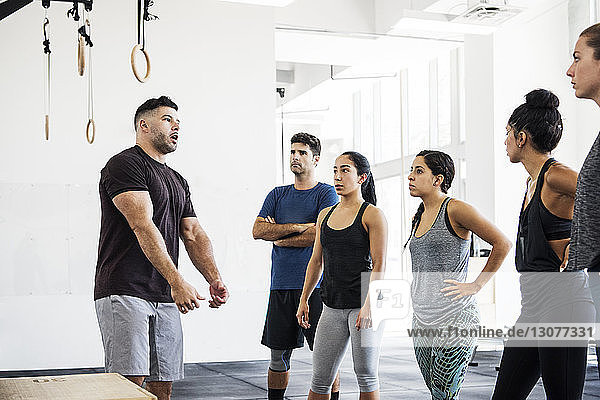 Athletes listening to instructor explaining in crossfit gym