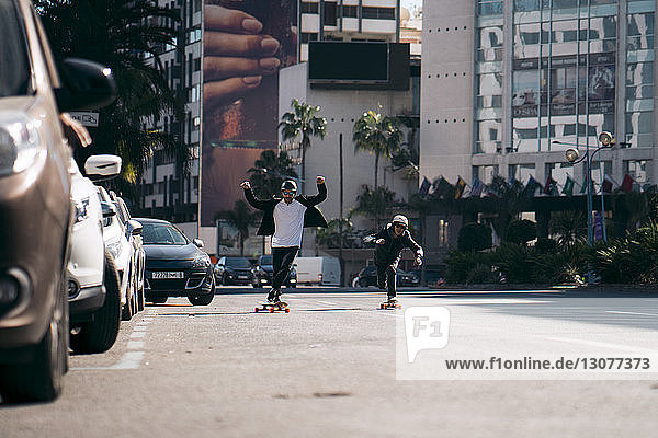 Männliche Freunde skateboarden bei Sonnenschein auf der Straße in der Stadt