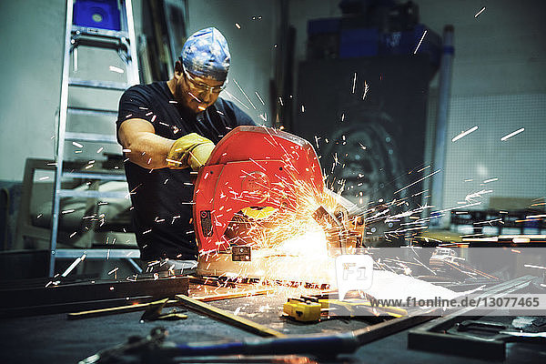 Handwerker  der im Werk Metallstangen mit einer Kreissäge schneidet