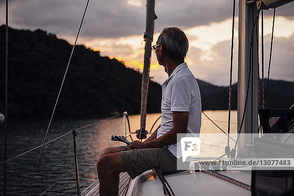 Älterer Mann schaut weg  während er auf einem Segelboot auf See reist