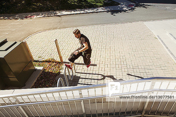Hochwinkelaufnahme eines Mannes  der einen Stunt auf einem Geländer in der Stadt macht