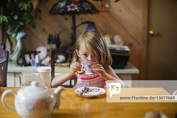 Porträt eines Mädchens  das Kaffee trinkt  während es an einem Holztisch sitzt