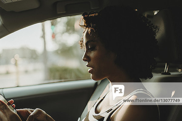 Nahaufnahme einer Frau  die ein Smartphone benutzt  während sie im Auto sitzt