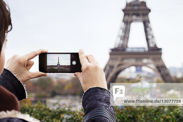Junge Frau fotografiert Eiffelturm mit Smartphone