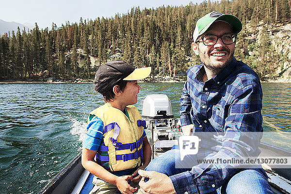 Happy father and son traveling in motorboat on lake