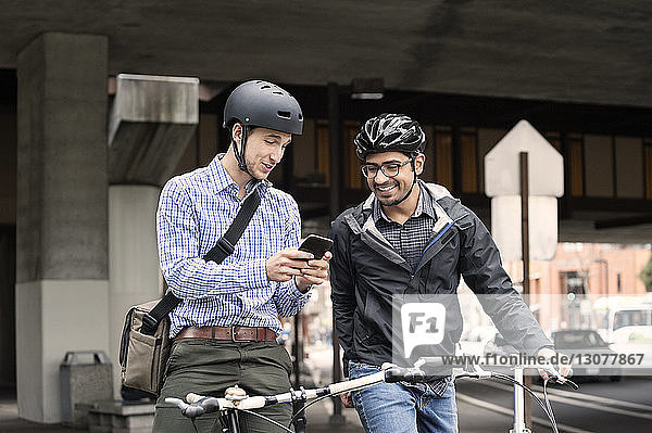 Multi-ethnic male commuters using smart phone on city street