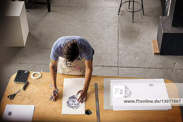 Hochwinkelansicht eines Arbeiters  der während der Arbeit in der Werkstatt skizziert