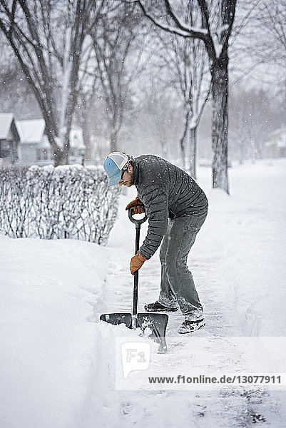 Full length of man shoveling snow from street