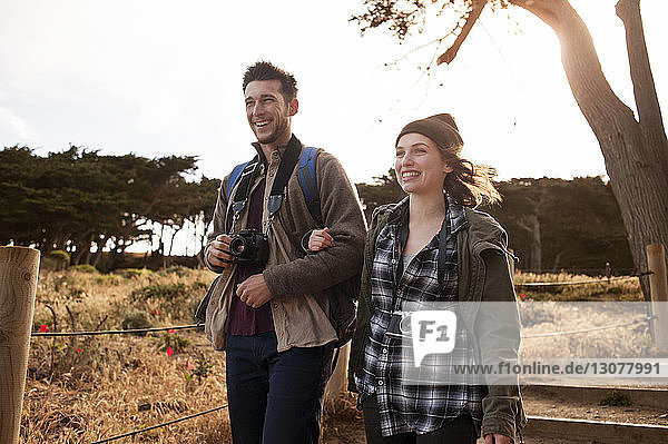 Happy hiking couple walking arm in arm on field