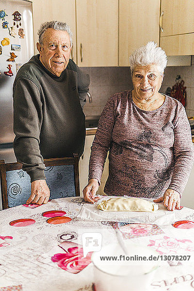 Porträt eines älteren Ehepaares  das in der Küche am Tisch steht