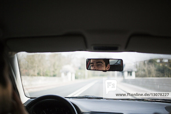 Spiegelung des Menschen im Autorückspiegel auf der Straße
