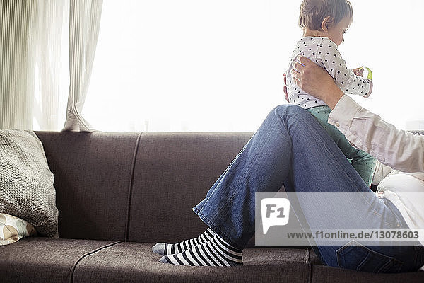 Niedriger Teil einer Frau  die mit ihrer Enkelin auf einem Sofa am Fenster sitzt