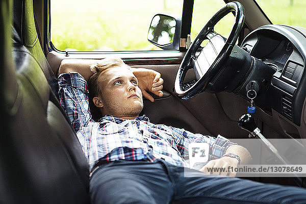 Mann schaut weg  während er sich im Pick-up entspannt