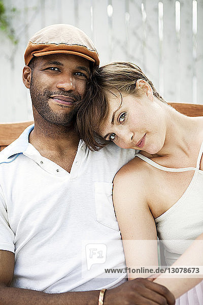 Portrait of couple sitting on chair in lawn