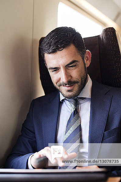 Businessman using tablet computer in train
